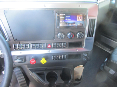 Dashboard of a Western Star truck cab showing infotainment screen, climate controls, hazard lights, knobs, and cup holders.