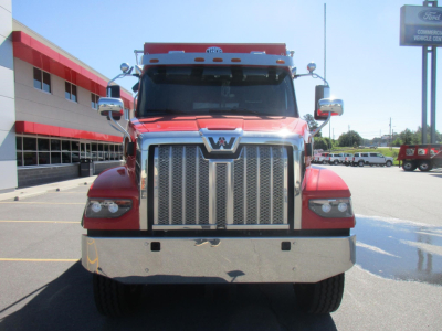 Front view of a red 2027 Western Star 47X dump truck showing large chrome grille, bumper, and dual side mirrors.