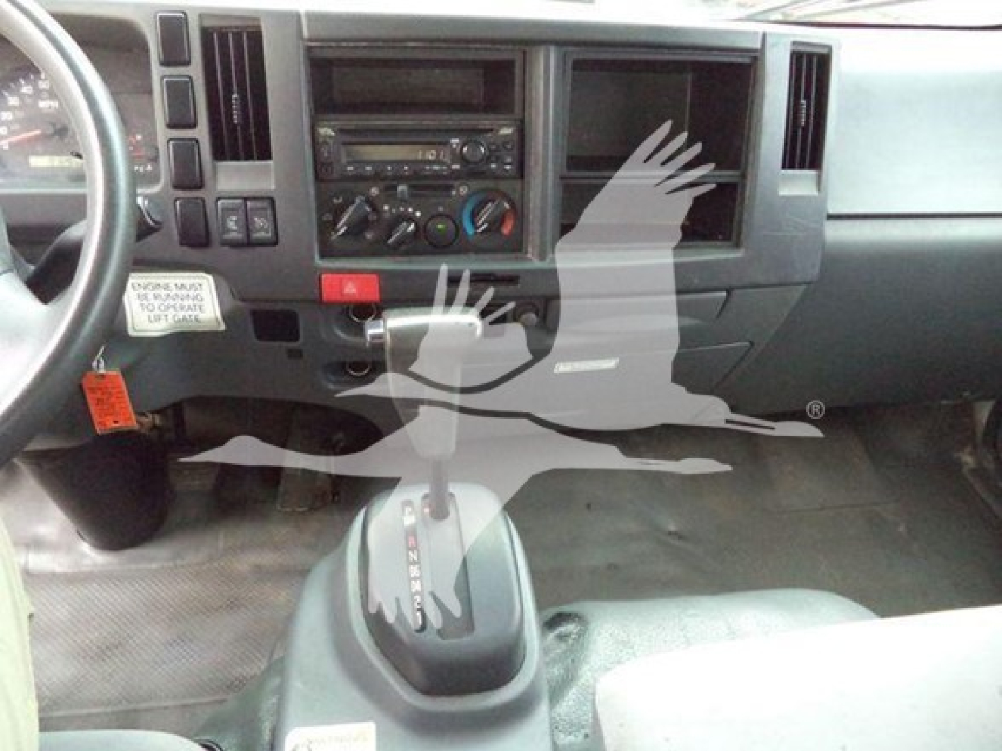 Isuzu NPR HD dashboard view with front console, gear shifter, and center controls showing radio/climate dials.