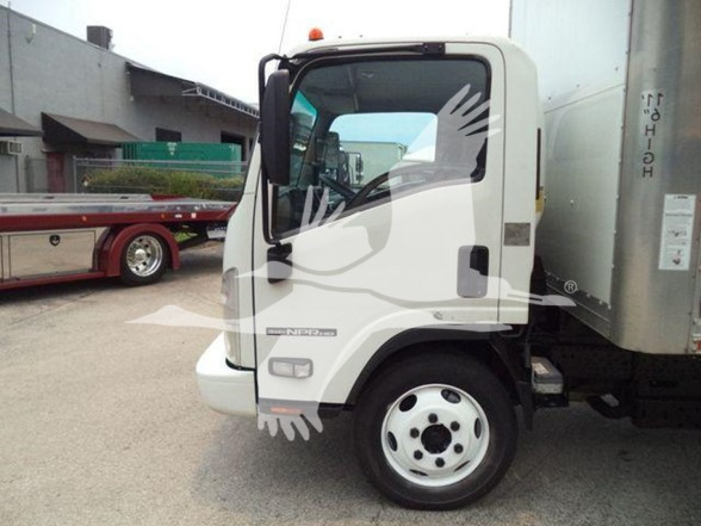 Isuzu NPR HD truck cab and box body view showing front fender, wheel, and side of cab with VIN/stock label area not visible.