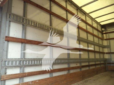 Isuzu NPR HD truck box interior showing metal wall rails and wooden floor supports.
