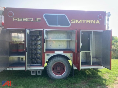 GMC 7000 rescue fire truck side compartments open showing equipment racks and hose reels; 'RESCUE' and 'SMYRNA' text on red body, wheel, rear doors open.