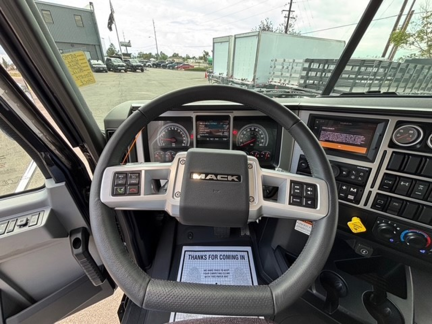 Dashboard and steering wheel of a 2026 Mack GR64F dump truck cab, showing Mack emblem on steering wheel and instrument cluster."