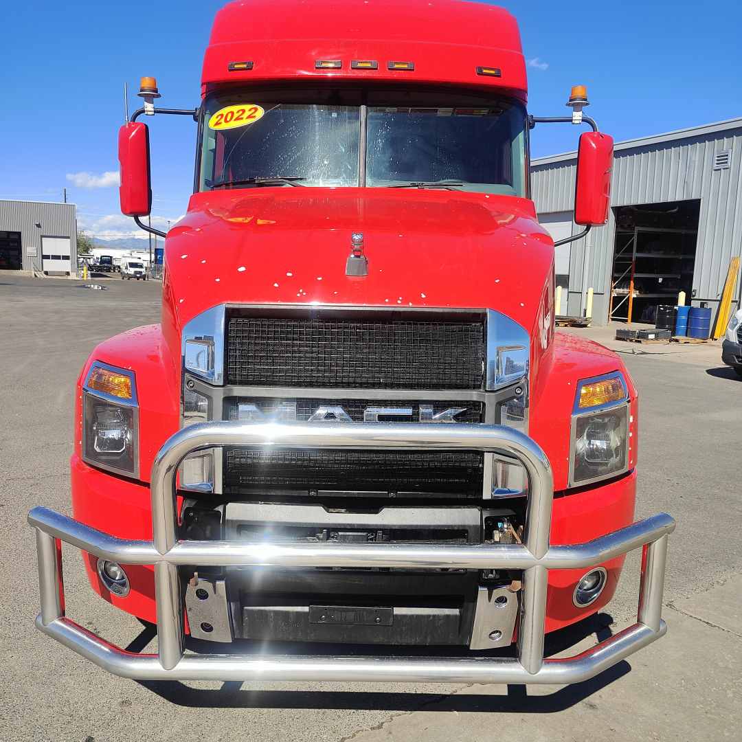 Front view of a red 2022 Mack AN64T70 heavy-duty truck with a chrome grille, bull bar, and amber marker lights on the cab roof.