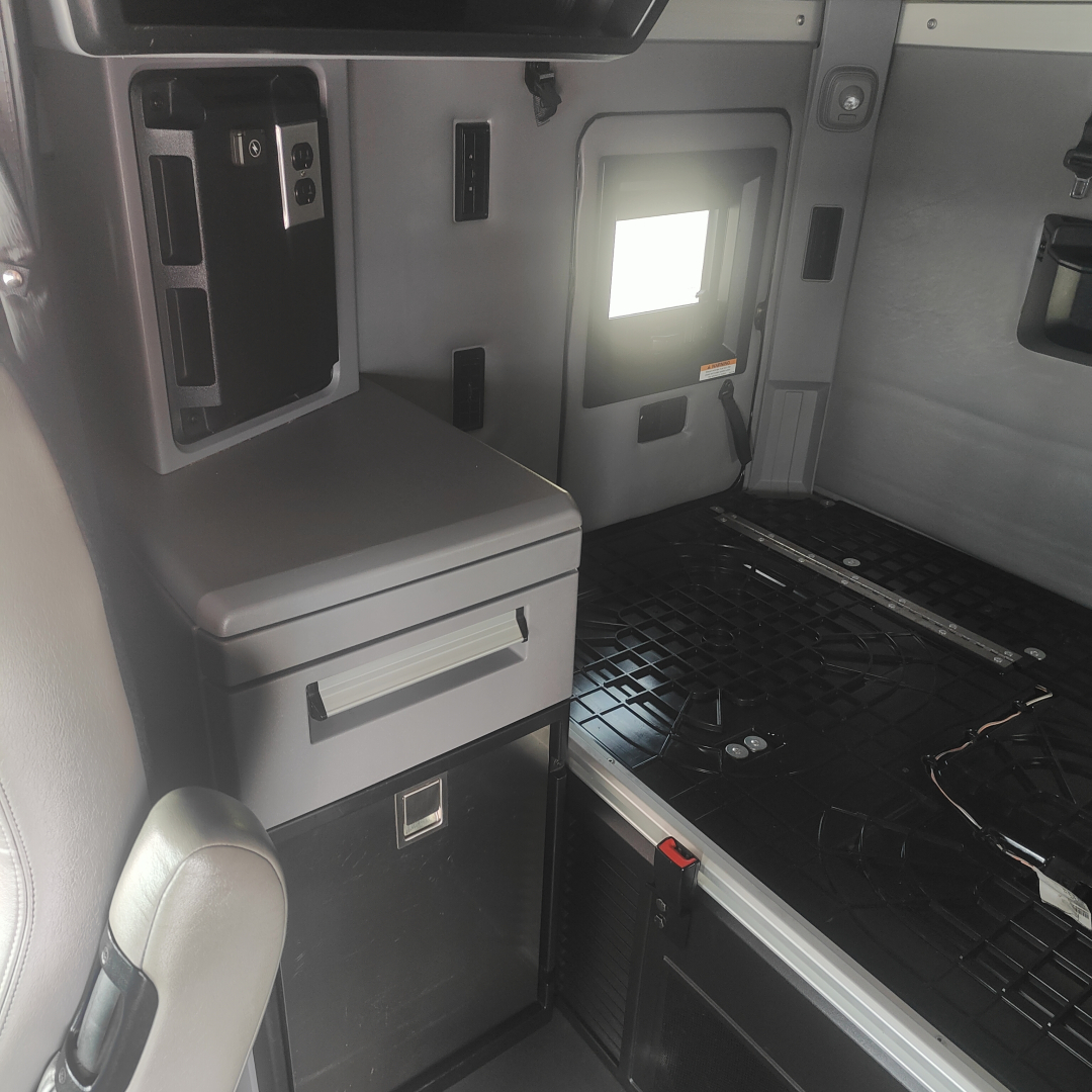 Truck cab interior showing storage drawers and control panel with window opening.