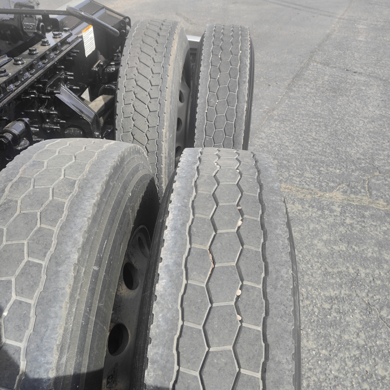 Truck rear wheels with dual rear axle and treaded tires in view; mechanical components and frame visible at left edge.