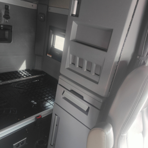 Interior view of a 2022 Mack AN64T70 sleeper cab showing storage compartments and driver's seat with dashboard panels.