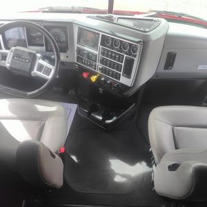 Mack truck cabin dashboard and steering wheel with control panel and gauges visible.