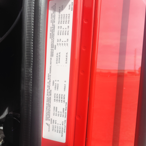 Label with vehicle specs inside door jamb on red truck showing VIN and weights text