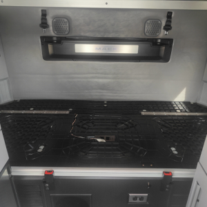 Mack AN64T70 truck bed area showing storage hatch, ventilation grills, and ventilation latches with a the Mack badge in a recessed frame.