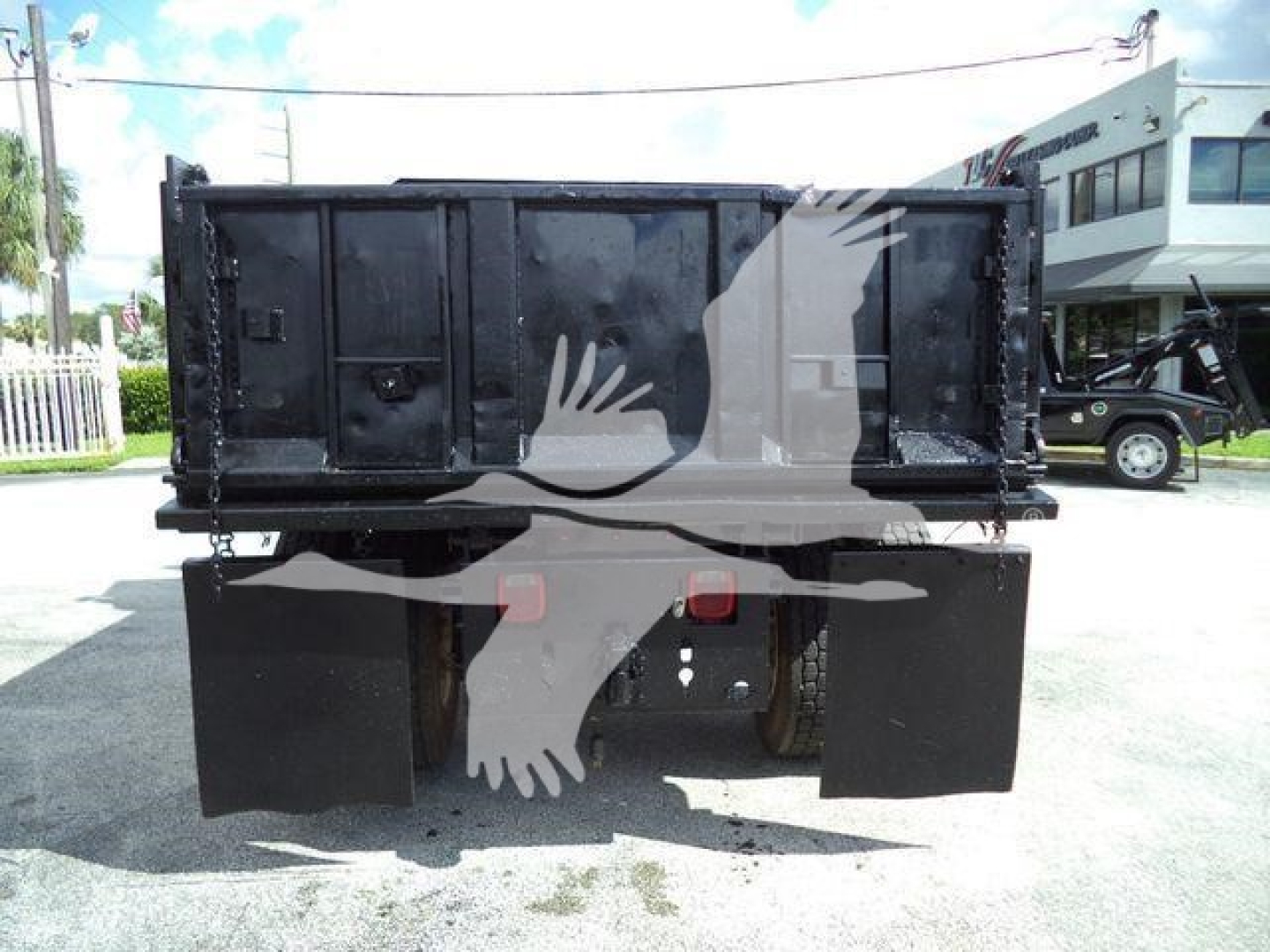 Dump truck bed rear view showing black metal dump box and dual rear mud flaps.
