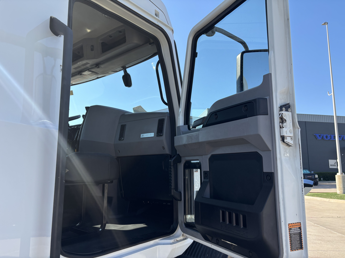 Truck cab interior of a 2022 Mack AN42T showing open door with dashboard and seating area visible.