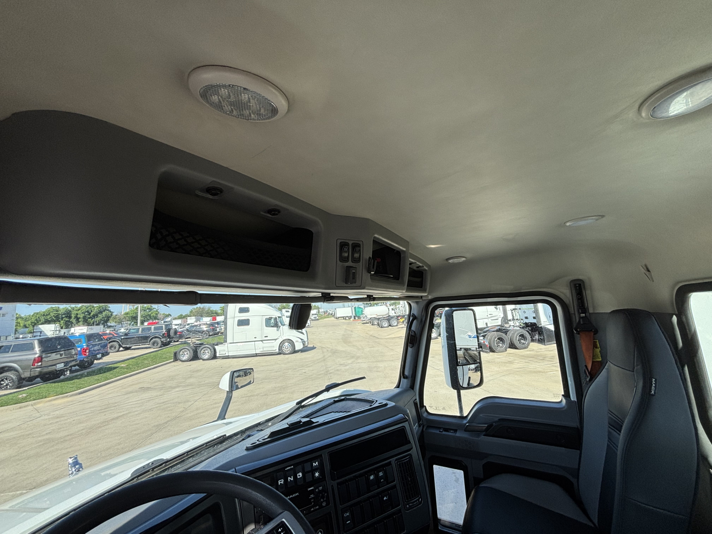 Cab interior of a 2022 Mack AN42T daycab showing dashboard controls, overhead compartments, and seating area.
