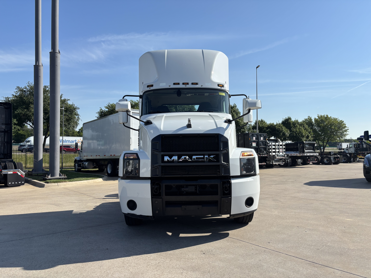 Front view of a white 2022 Mack AN42T conventional daycab truck, showing grille with MACK letters, large bumper, side mirrors, and tall sleeper window on a dealership lot.