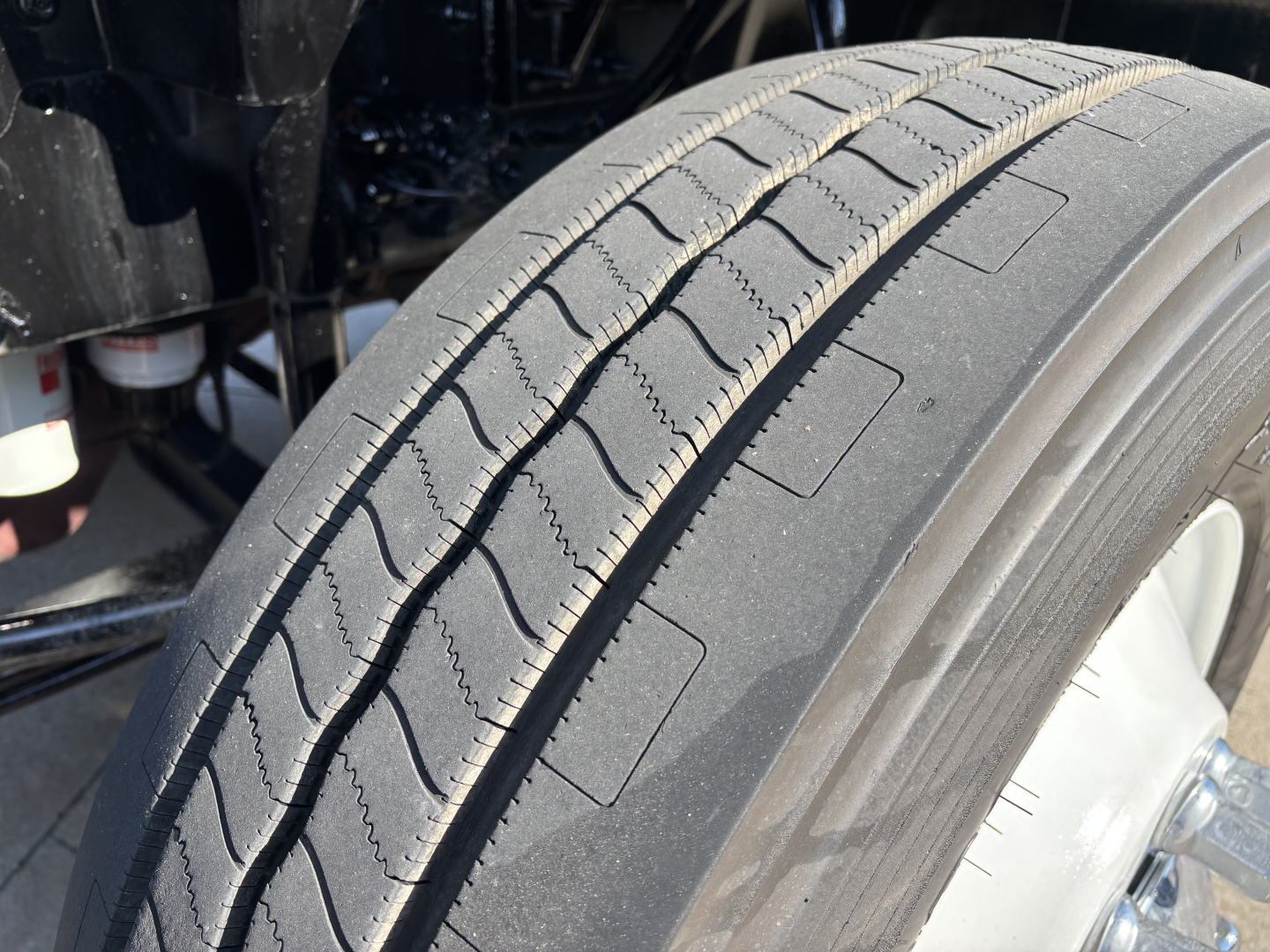 Tire tread and wheel under Mack AN42T truck showing front duals and suspension components.