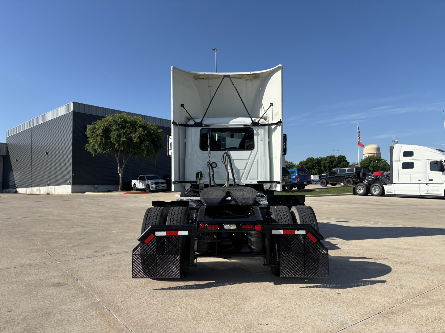Back view of a semi truck tractor with a raised trailer reveal, two large rear tires, mudflaps, and chassis; no visible text readable on components.