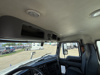 Cab interior of a 2022 Mack AN42T daycab showing dashboard controls, overhead compartments, and seating area.