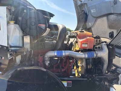 Engine bay of a 2022 Mack AN42T daycab showing engine components, hoses, and coolant reservoir.