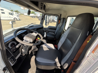 Mack AN42T cab interior showing steering wheel, dashboard, driver's seat, and passenger seat. Photo from the open door reveals instrument cluster and controls.