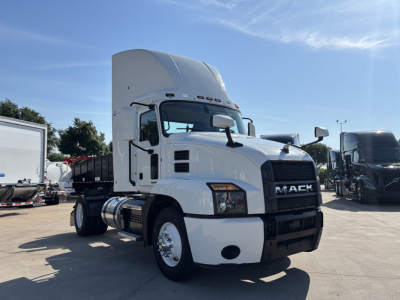 Mack AN42T conventional daycab truck in a dealership lot, white cab, large aerodynamic sleeper, front grille with Mack lettering, chrome front bumper, diesel fuel tanks