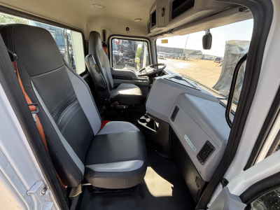 Interior of a 2022 Mack AN42T cab showing front seats and dashboard with steering wheel, grey panels, and door on the left.