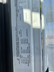 Label on Mack AN42T truck showing vehicle identification and specifications including VIN 1M1AN2AY7NM002754, stock number B3251P, category conventional daycab, year 2022, and various weights.
