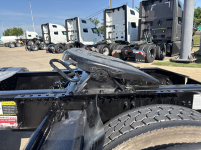 Mack AN42T truck cab and frame with wheel and deck area visible; hydraulic fifth wheel mount and control lever; other truck cabs in background.