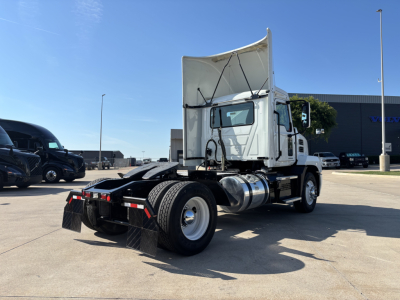 Truck with raised sleeper cab showing AN42T chassis, rear view. Fuel tanks, dual rear axles, and lifting hood visible on white Mack truck.