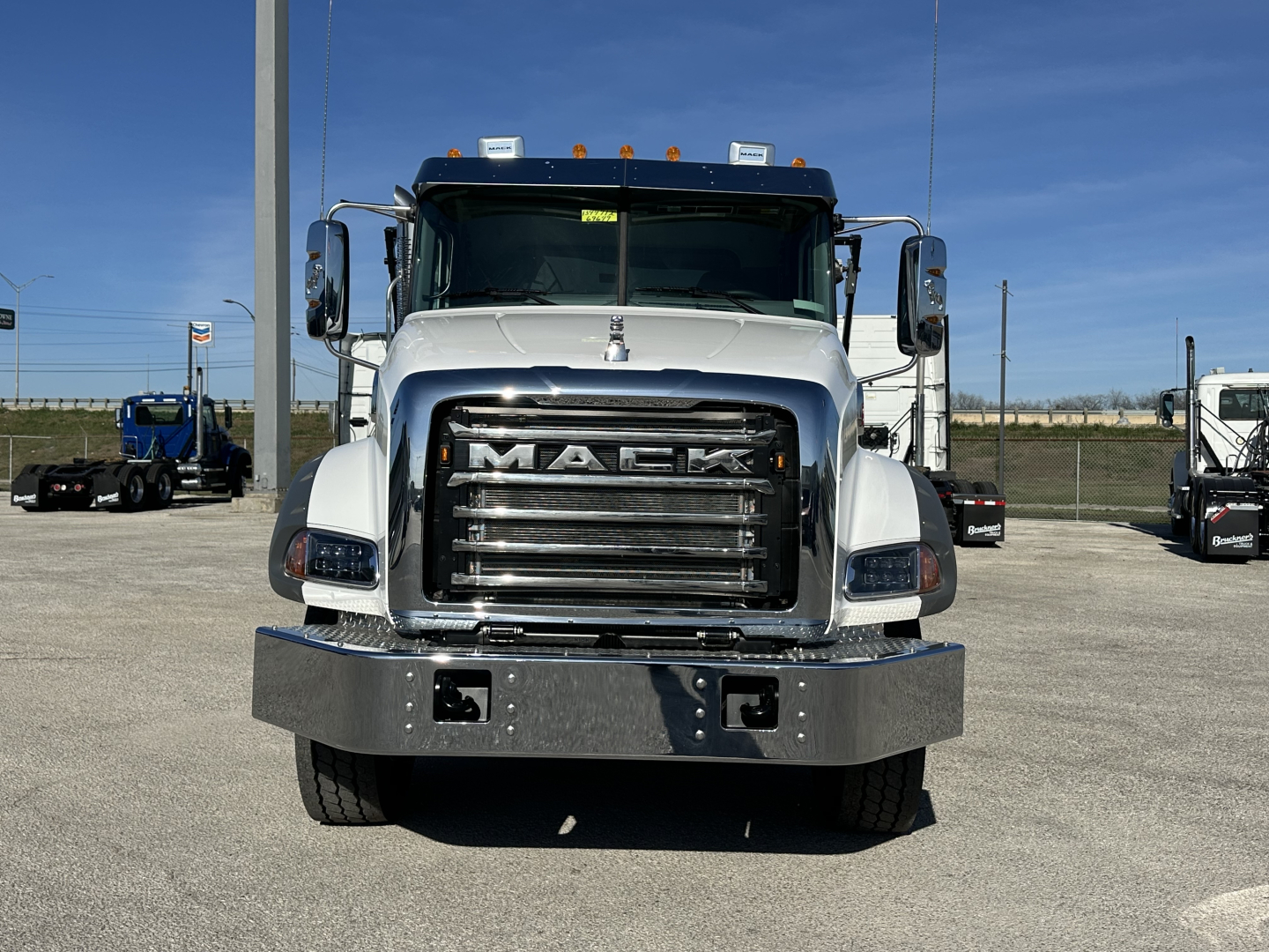 Front view of a new 2026 Mack GR64B roll-off truck showing chrome grille with MACk logo, large bumper, and side mirrors.