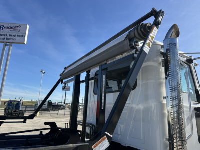 Mack GR64B roll-off truck side view showing hydraulic hoist system with cylindrical drum and chrome exhaust stack