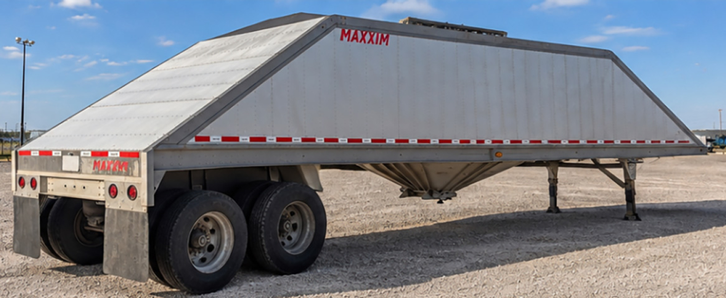 MAXXIM SAND HOPPER trailer showing side profile with dual rear axles and triangular hopper body.