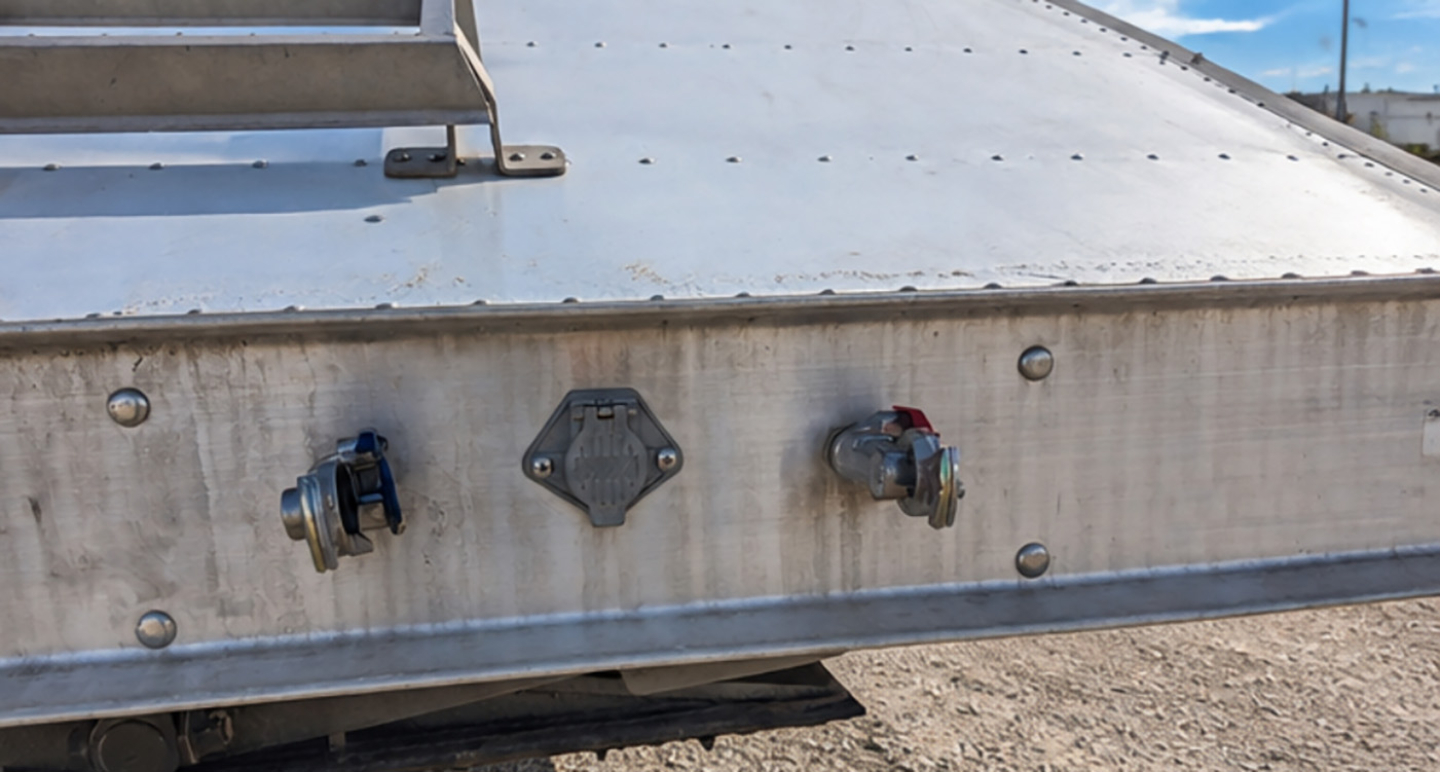 Rear view of MAXXIM SAND HOPPER trailer showing inlet/outlet valves and central access plate on aluminum side panel.
