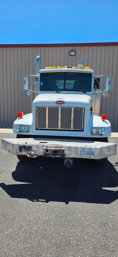 Peterbilt 330 front view showing large chrome grille, headlights, bumper with winch, license plate, and amber roof lights.