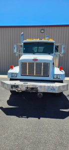 Peterbilt 330 front view showing large chrome grille, headlights, bumper with winch, license plate, and amber roof lights.