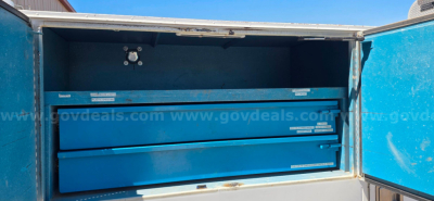 Blue toolbox drawers visible in an open service compartment on a Peterbilt truck, metallic labels on drawers.