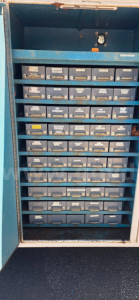 Tool storage cabinet with many labeled small drawers in a blue metal cabinet.
