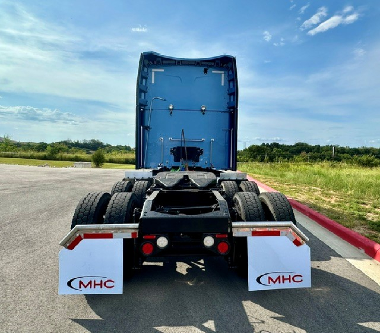 Peterbilt 579 rear view showing fifth wheel, dual rear axles, and mud flaps with MHC logo.