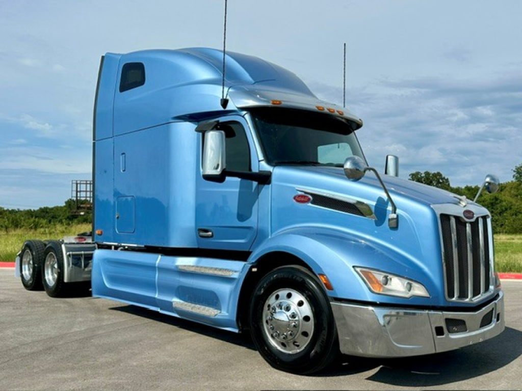 Peterbilt 579 tractor in blue, side view showing sleeper cab and chrome front bumper, single axle, daytime setting.