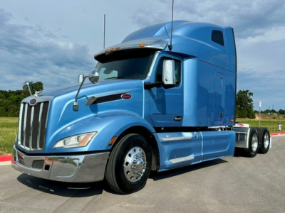 Peterbilt 579 tractor in blue, side view, with sleeper cab and chrome front bumper.