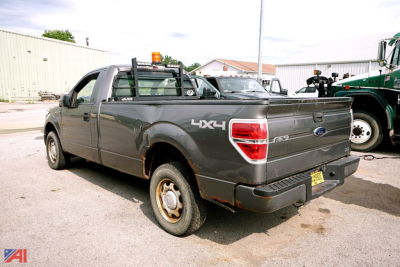 Ford F-150 pickup truck 4x4 rear quarter view showing bed with toolbox, tailgate with Ford emblem, and 4x4 decal.