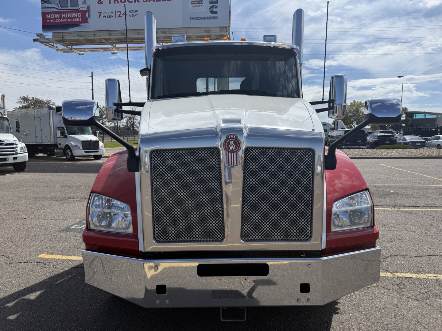 Kenworth T880 front view showing large chrome grille, dual mesh panels, tall mirrors, and chrome bumper in a truck lot.