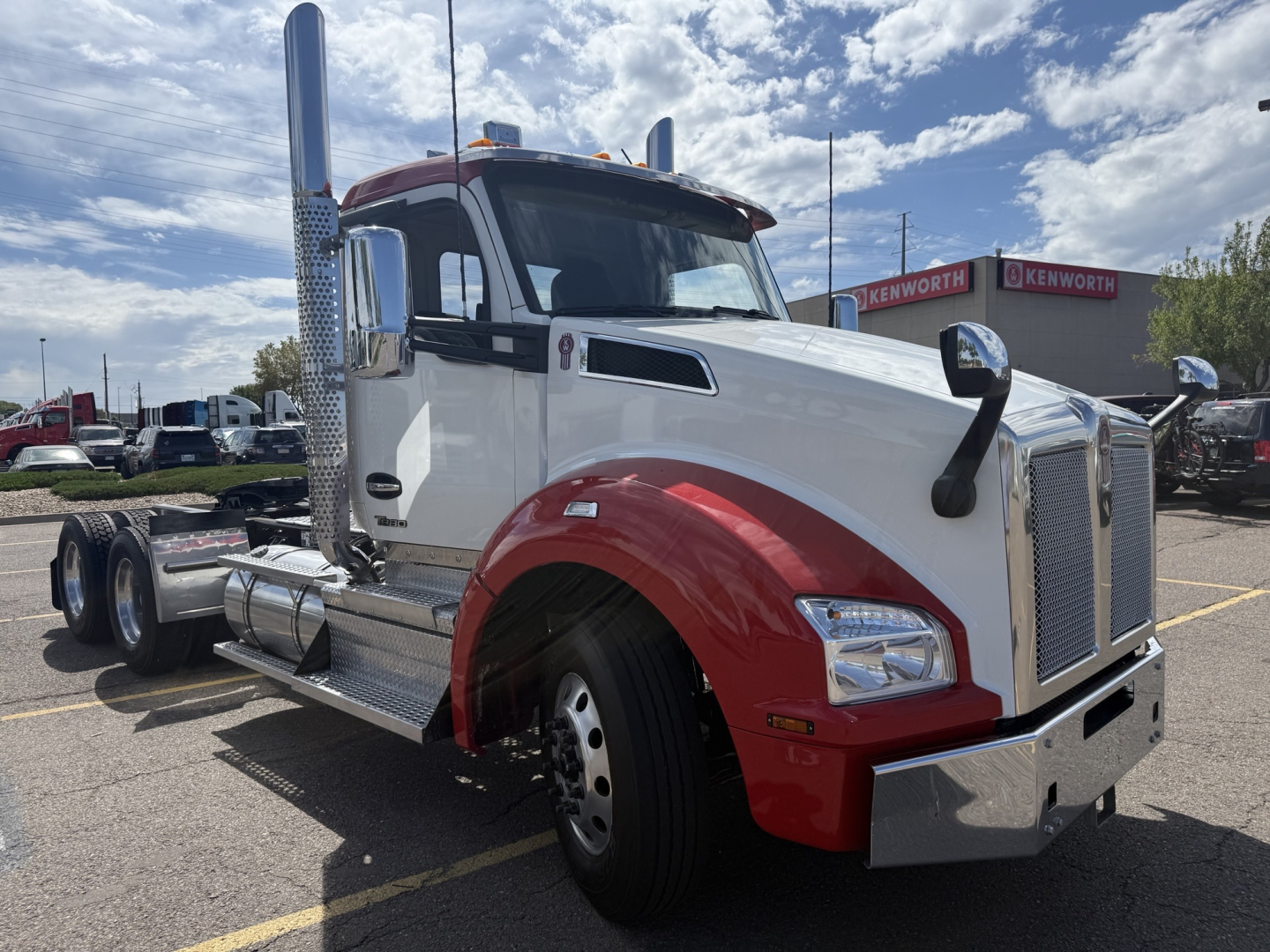 Truck cab and chassis of a white Kenworth T880 with red fenders, dual exhaust stacks, large chrome grille, and a chrome bumper.