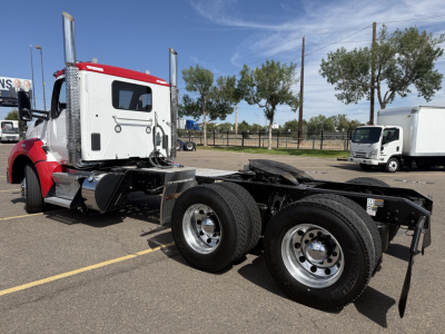 Kenworth T880 conventional daycab chassis view showing dual rear axles and fuel tanks.