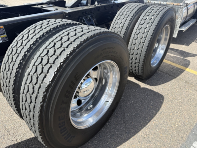 Kenworth T880 dual rear axle wheels and tires in view; glossy chrome wheel rims; treaded dual tires; part of truck chassis visible.