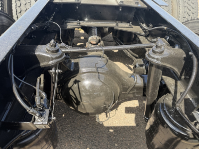 Vehicle rear axle view showing suspension components and differential housing beneath the frame of a Kenworth T880 truck.