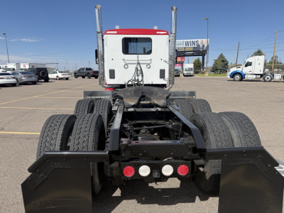 Kenworth T880 truck chassis rear view showing dual rear axles and fifth wheel with mud flaps and warning lights.