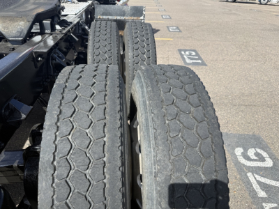 Kenworth T880 truck chassis and dual rear wheels in a parking lot showing treaded tires.