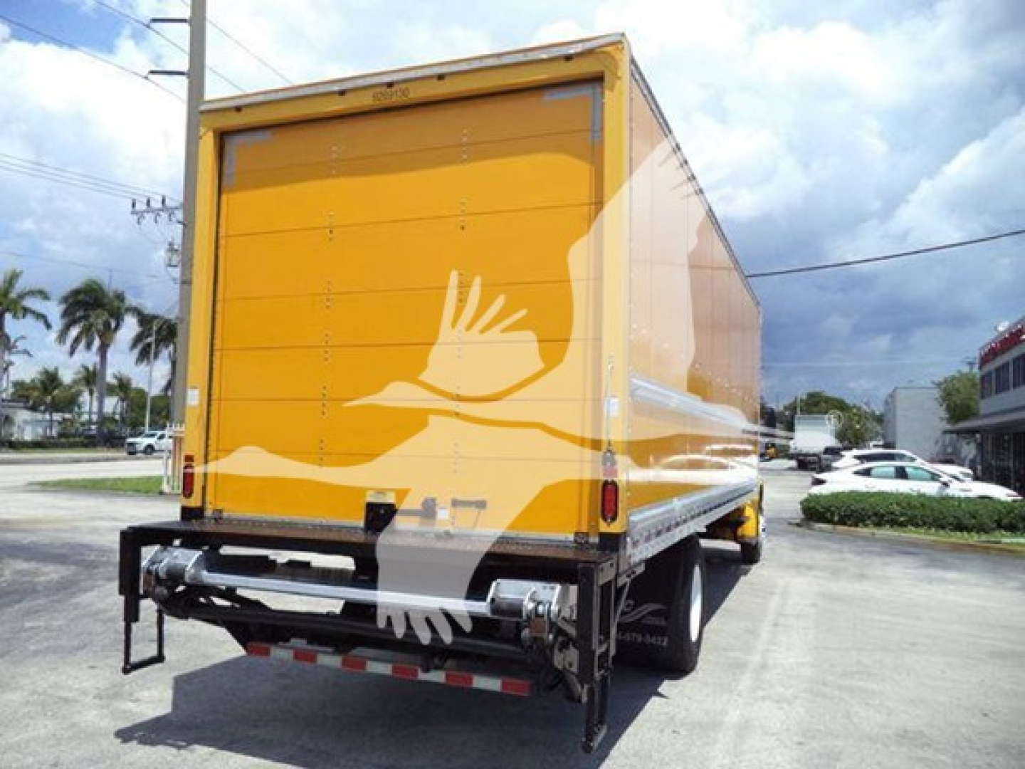 Freightliner M2 106 box truck rear view showing yellow cargo area and rear hydra lift with bumper and taillights.