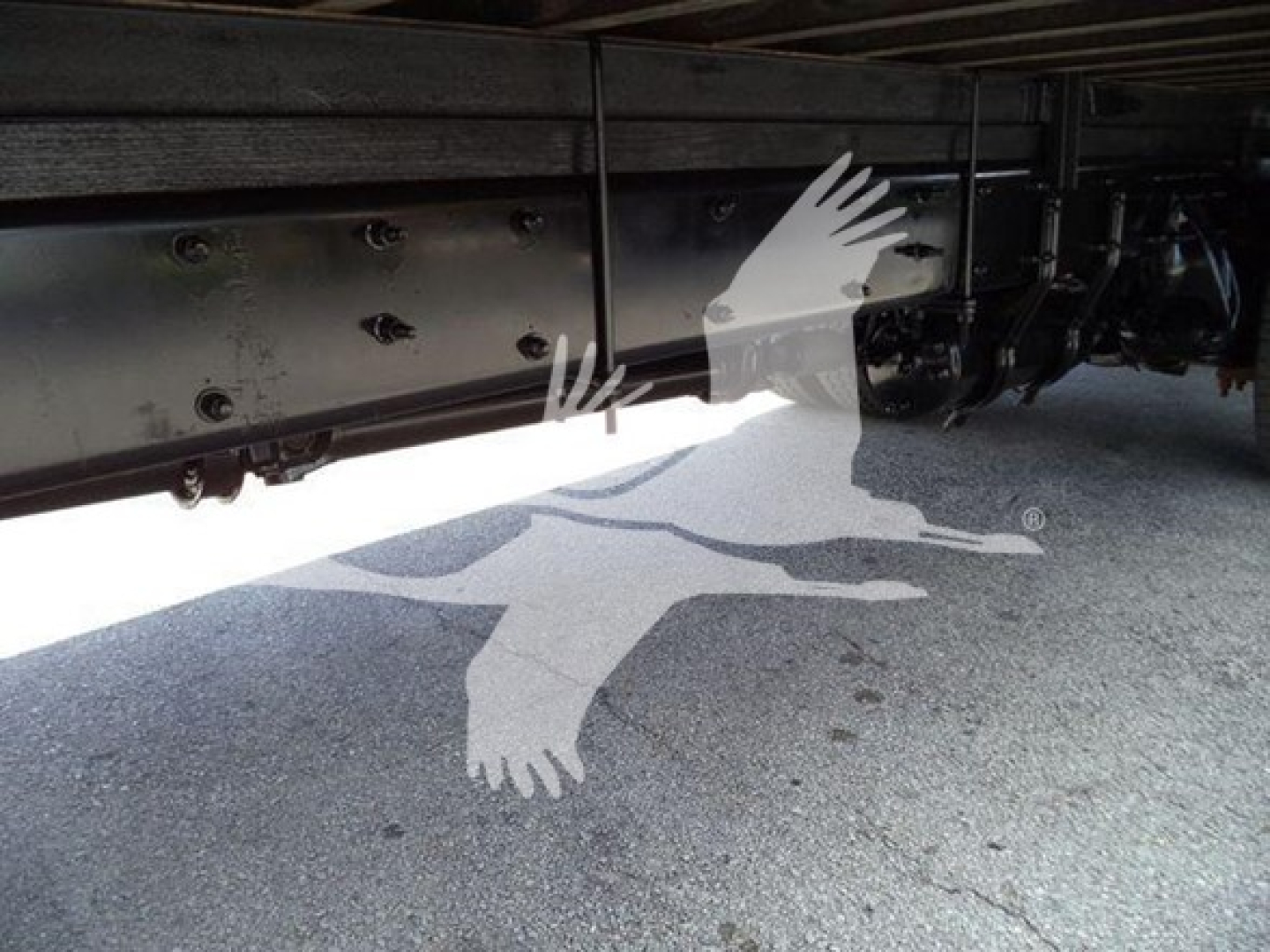 Underbelly of a Freightliner M2 106 truck showing chassis rails and frame with bolts and brackets.