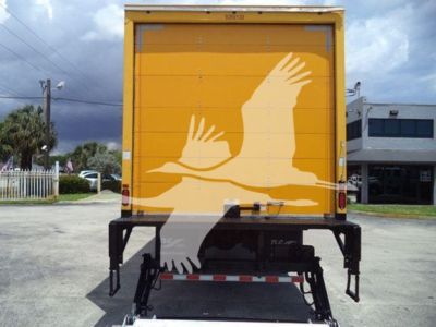 Rear view of a 2019 Freightliner M2 106 box truck with a bright yellow cargo door featuring a white bird graphic. Tail area shows black chassis, brackets, and reflectors.